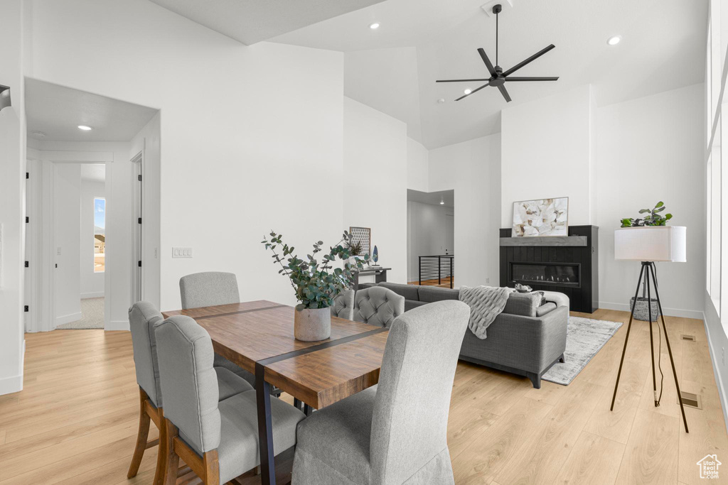 Dining area with high vaulted ceiling, light wood finished floors, ceiling fan, baseboards, and recessed lighting