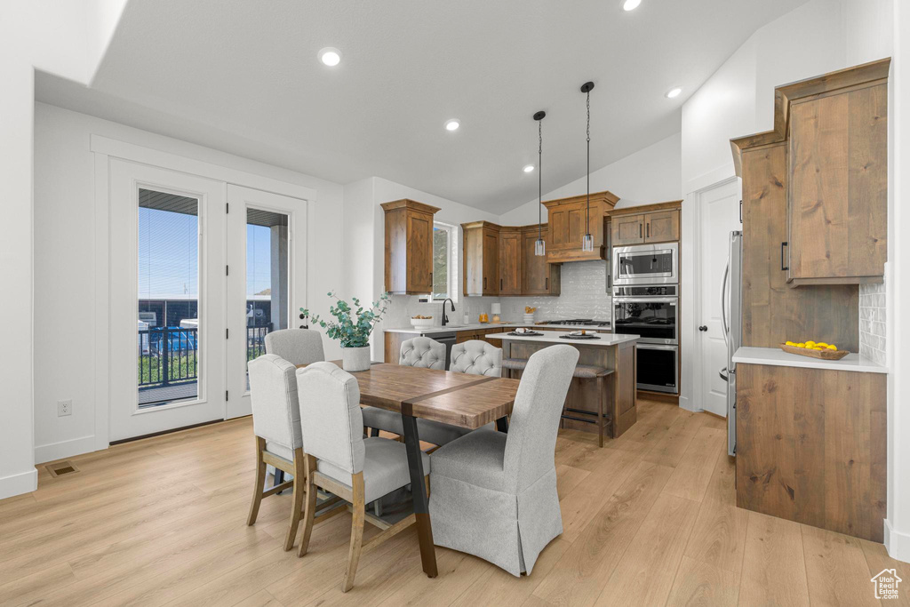 Dining area with vaulted ceiling, light wood-type flooring, and recessed lighting