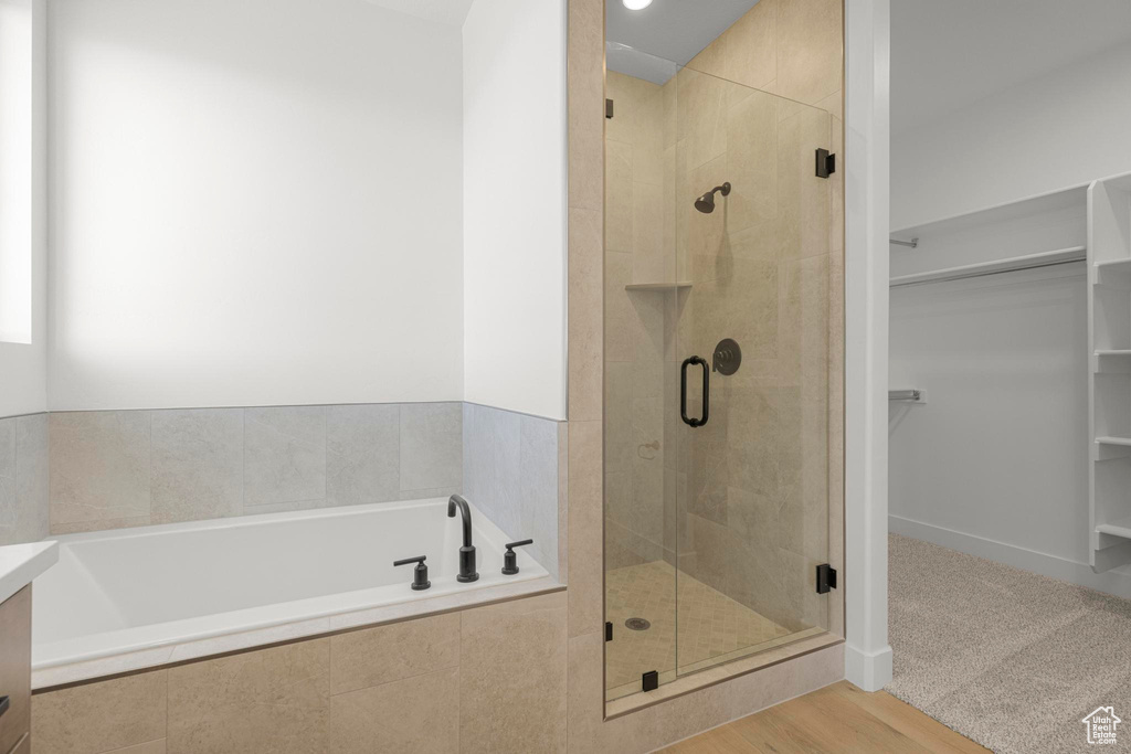 Full bath with a stall shower, a walk in closet, and a garden tub