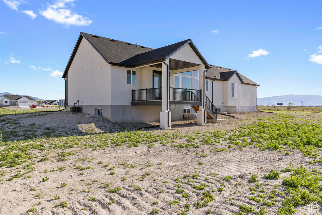 Back of property featuring stairs, a mountain view, central AC, and roof with shingles