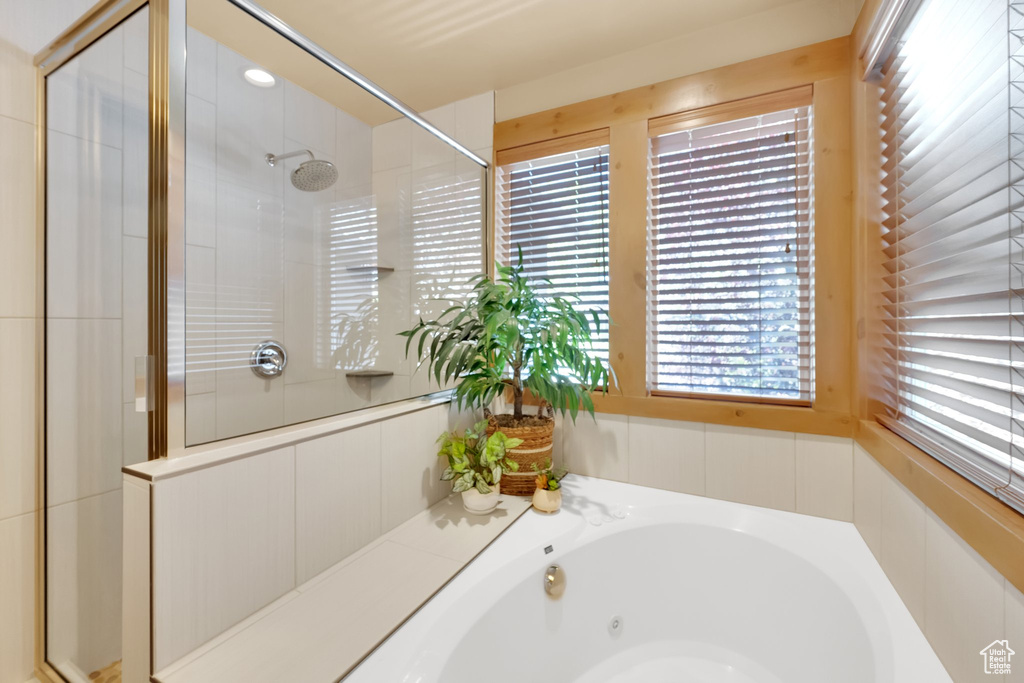 Bathroom featuring plenty of natural light, a tile shower, and a tub with jets