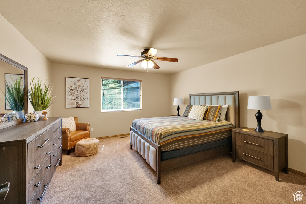 Bedroom with light carpet, baseboards, and a ceiling fan
