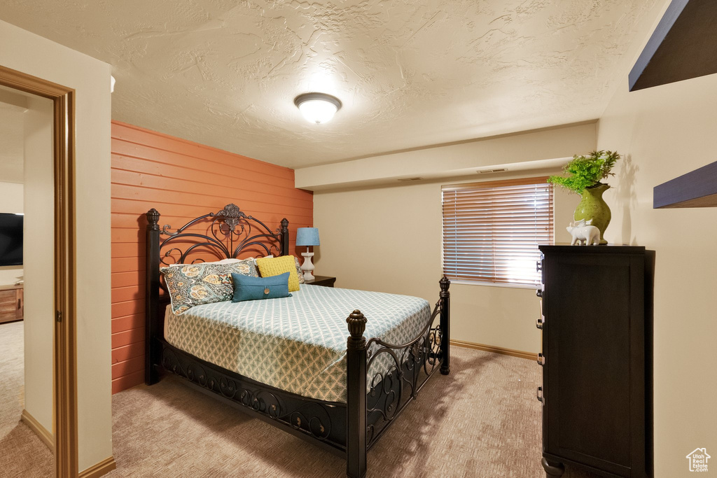 Carpeted bedroom featuring a textured ceiling, wooden walls, and baseboards