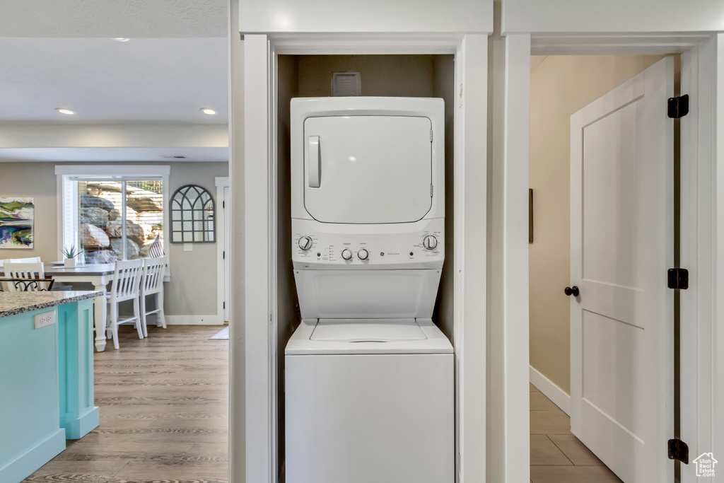 Laundry room featuring estacked washer and dryer, light wood finished floors, baseboards, and recessed lighting