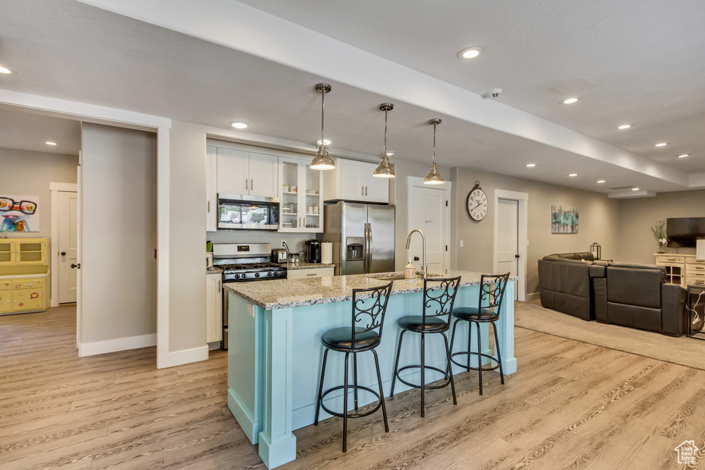 Kitchen with appliances with stainless steel finishes, light wood-style floors, a sink, a kitchen island with sink, and recessed lighting
