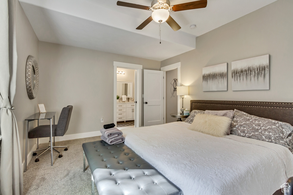 Carpeted bedroom featuring baseboards, ensuite bath, and a ceiling fan