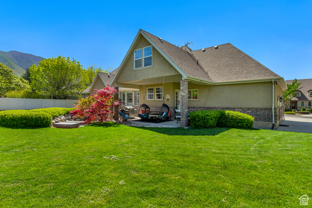 Back of property with stucco siding, a patio, roof with shingles, and brick siding