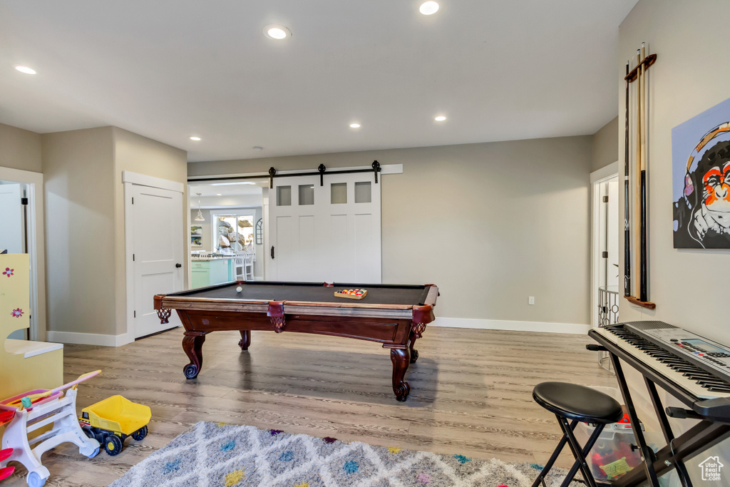 Game room featuring light wood-type flooring, baseboards, recessed lighting, pool table, and a barn door