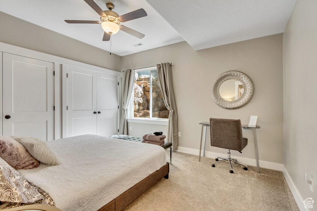 Bedroom with light carpet, baseboards, and a ceiling fan