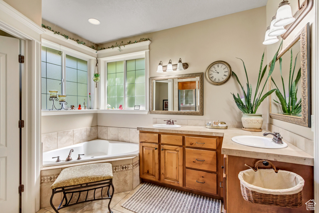 Full bath featuring tile patterned flooring, double vanity, and a bath