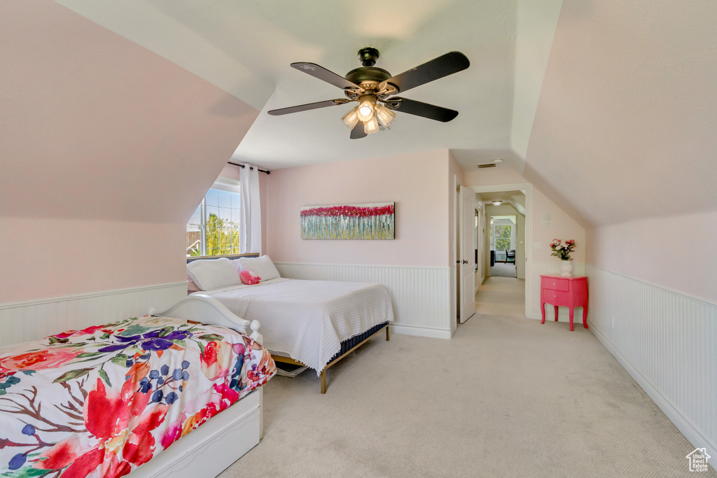 Bedroom featuring multiple windows, vaulted ceiling, wainscoting, carpet floors, and ceiling fan