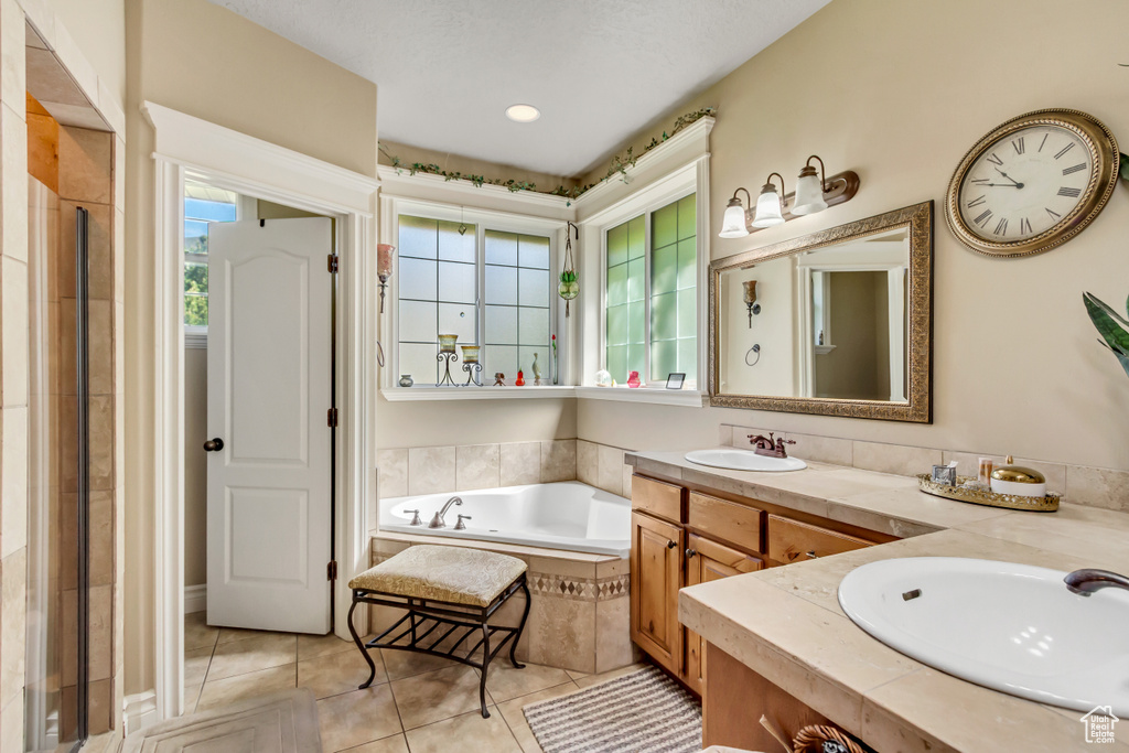 Bathroom with tile patterned flooring, a garden tub, double vanity, and tiled shower
