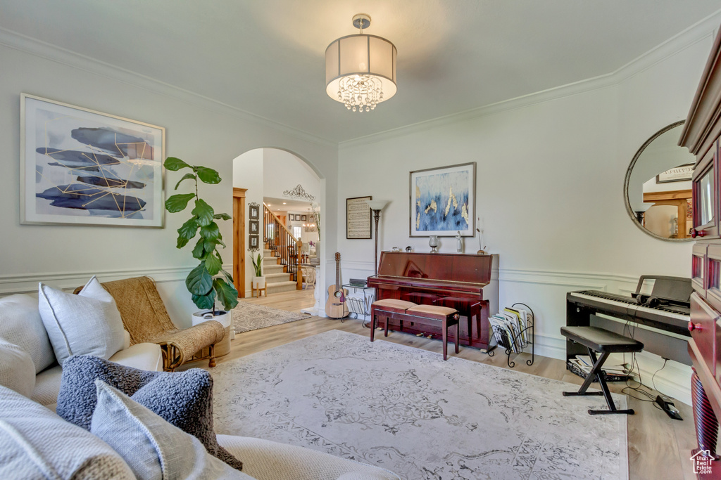Living room featuring arched walkways, crown molding, wood finished floors, stairs, and wainscoting