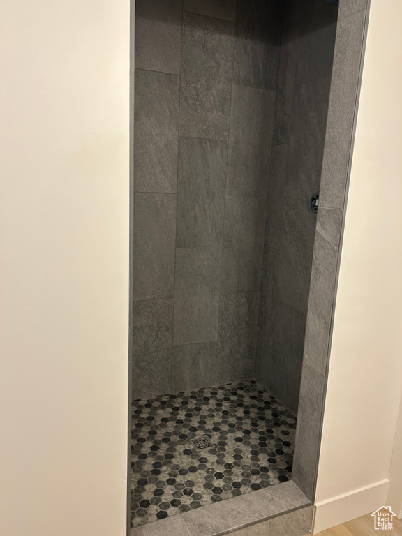 Full bathroom featuring tiled shower and wood finished floors