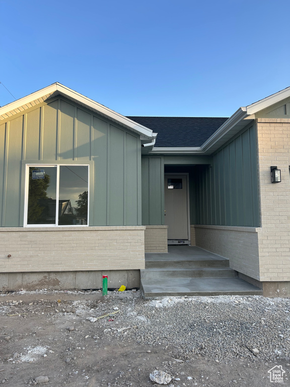 Property entrance with board and batten siding and brick siding