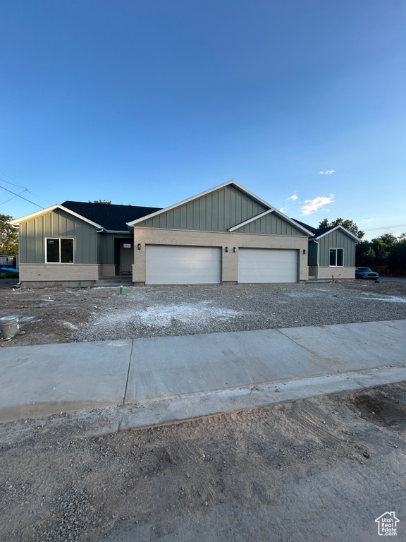 View of front of house featuring board and batten siding, an attached garage, and driveway