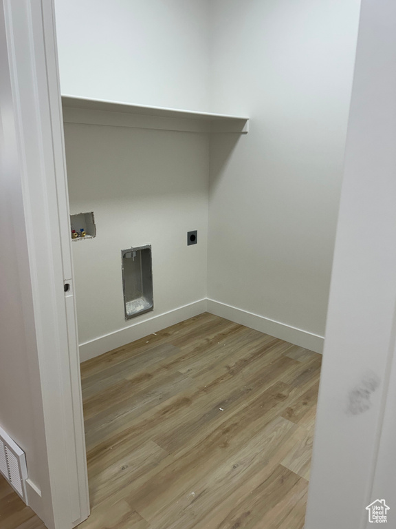 Washroom with light wood-type flooring, hookup for a washing machine, and electric dryer hookup