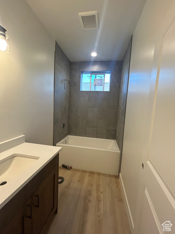 Bathroom with wood finished floors, vanity, and shower / bathtub combination