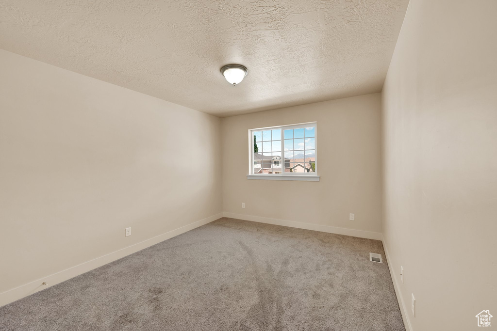Unfurnished room with a textured ceiling, carpet, and baseboards