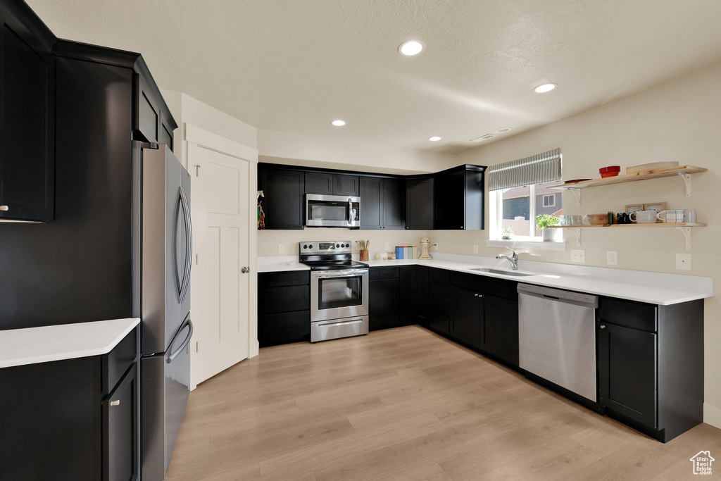 Kitchen with appliances with stainless steel finishes, dark cabinetry, a sink, and recessed lighting
