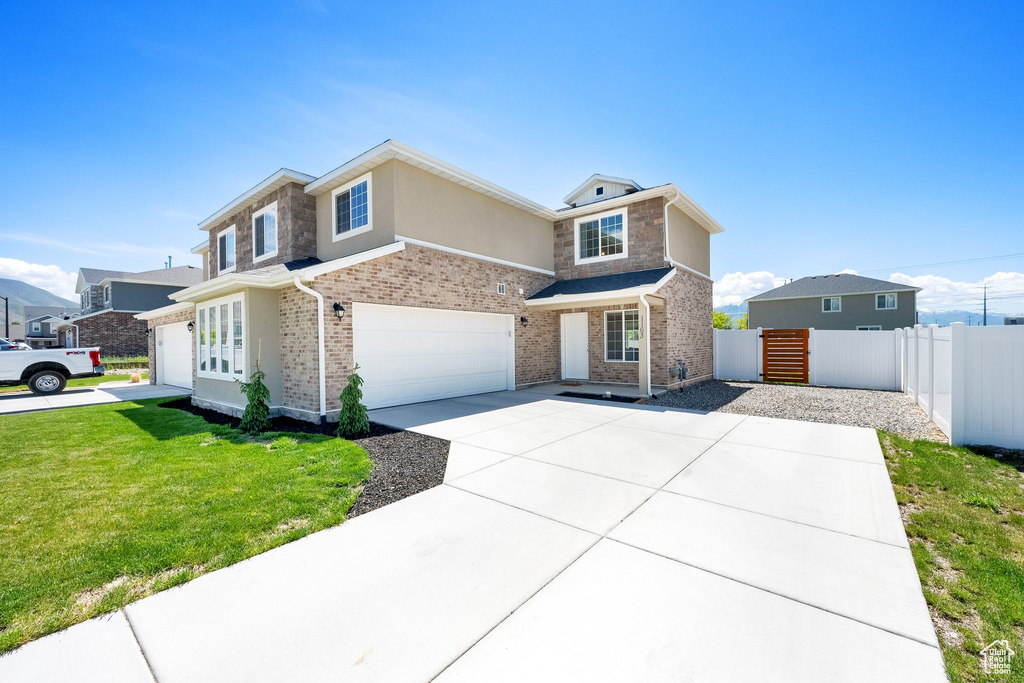 Traditional home featuring a garage, driveway, stucco siding, brick siding, and stone siding