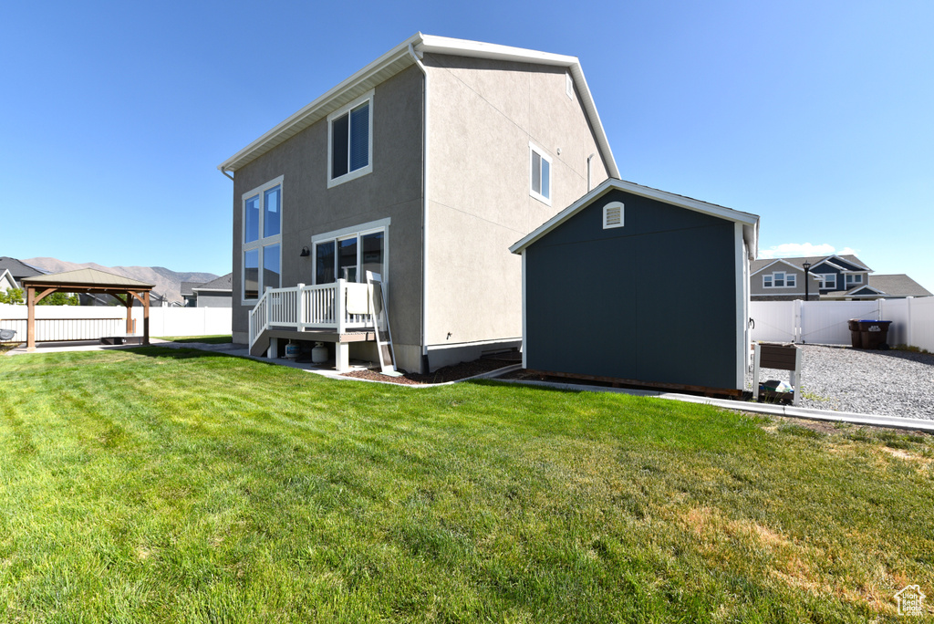 Back of house with a gazebo, stucco siding, and a storage unit