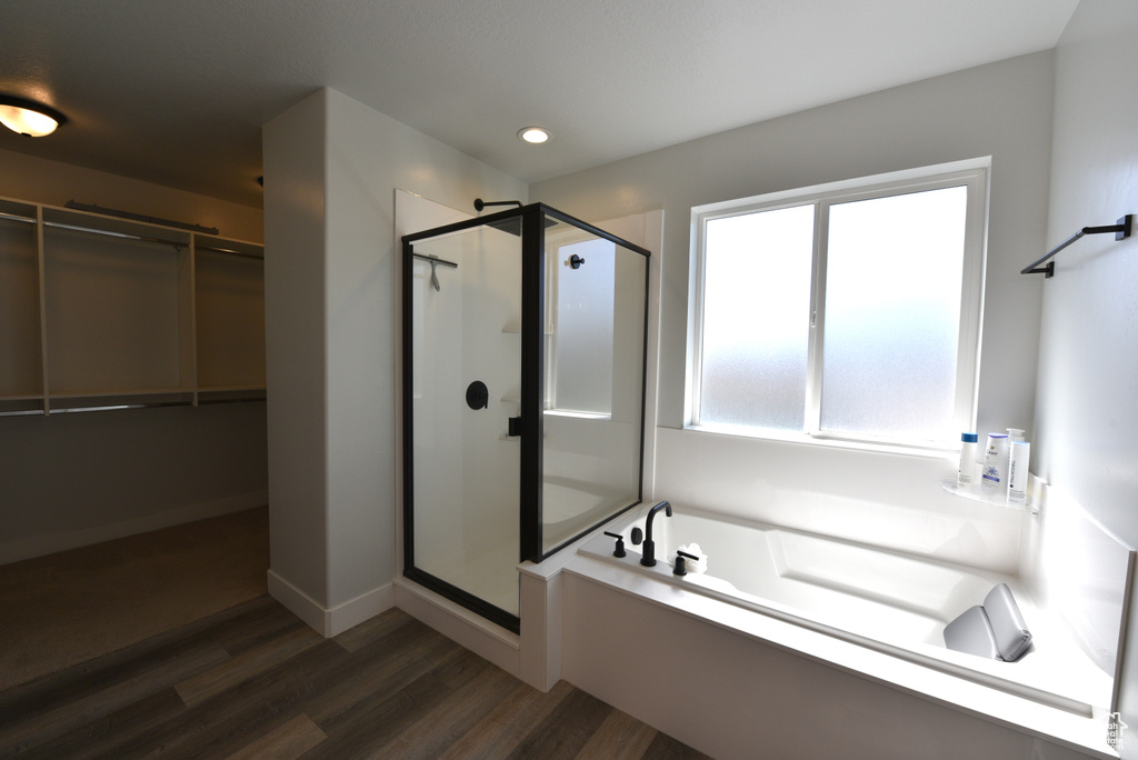 Bathroom with a shower stall, a garden tub, a spacious closet, wood finished floors, and recessed lighting