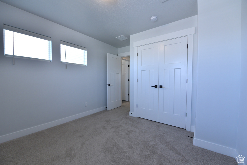 Unfurnished bedroom featuring carpet and a closet