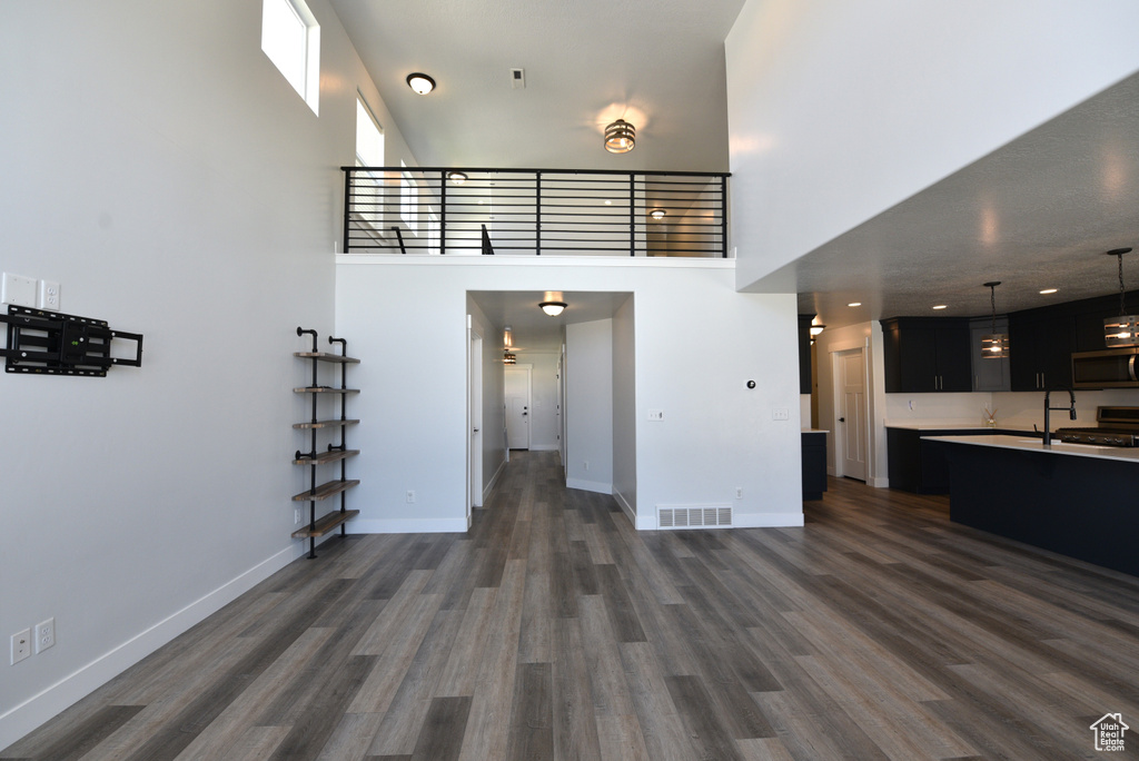 Unfurnished living room featuring a high ceiling and dark wood-style flooring