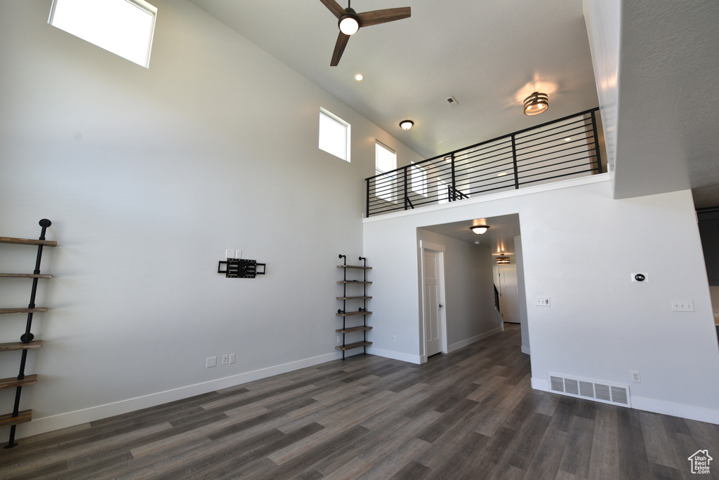 Unfurnished living room featuring a towering ceiling, a ceiling fan, dark wood-style flooring, and recessed lighting