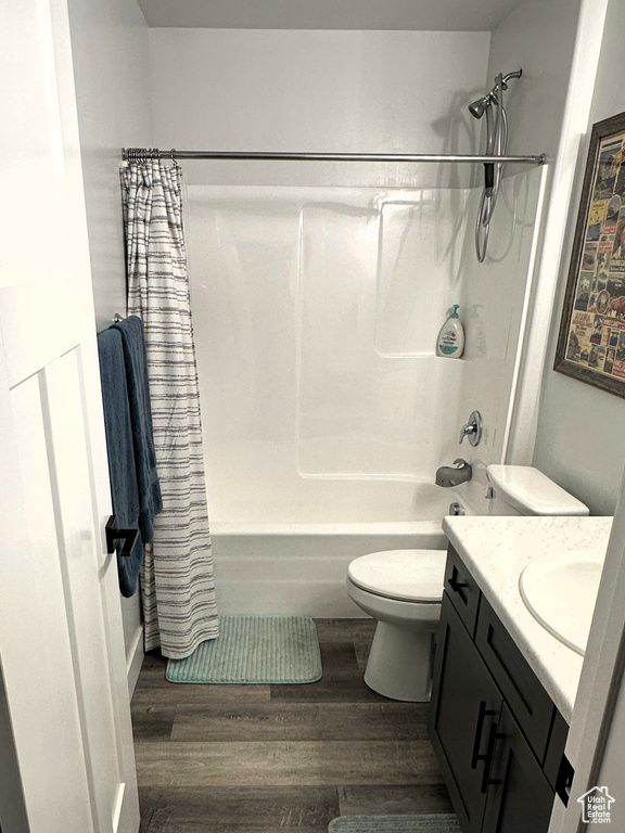 Bathroom featuring wood finished floors, toilet, shower / tub combo, and vanity