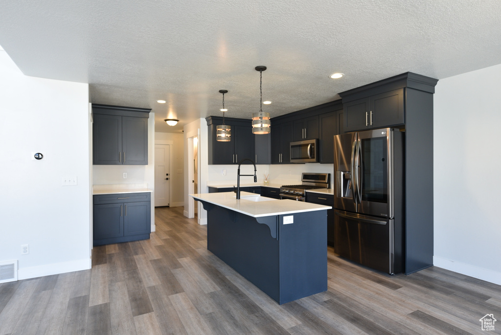 Kitchen featuring stainless steel appliances, dark wood-style floors, a kitchen breakfast bar, an island with sink, and recessed lighting