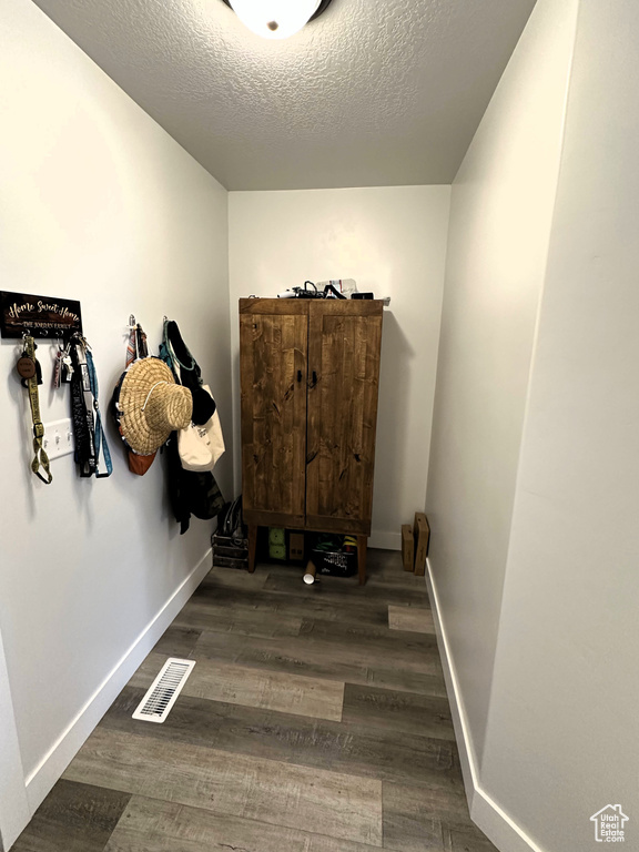 Corridor featuring a textured ceiling, wood finished floors, and baseboards