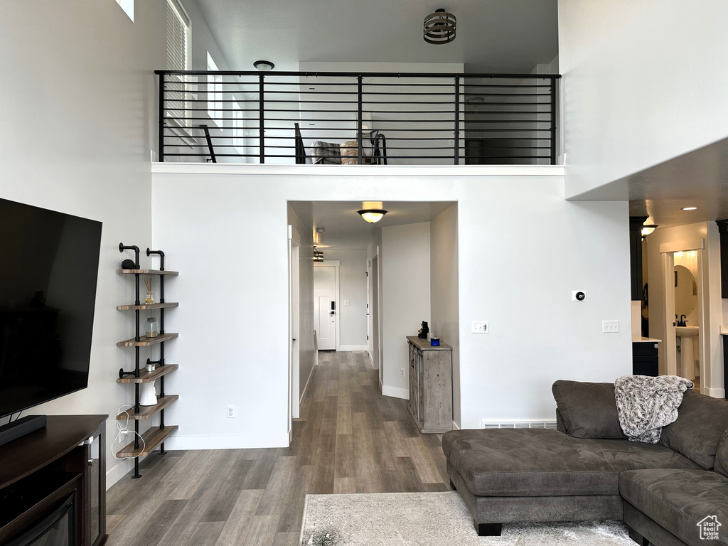 Living room featuring a towering ceiling, wood finished floors, and baseboards