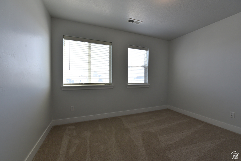 Unfurnished room featuring light carpet and baseboards