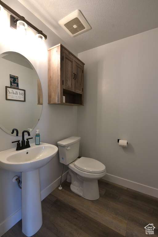 Half bathroom featuring wood finished floors and a textured ceiling