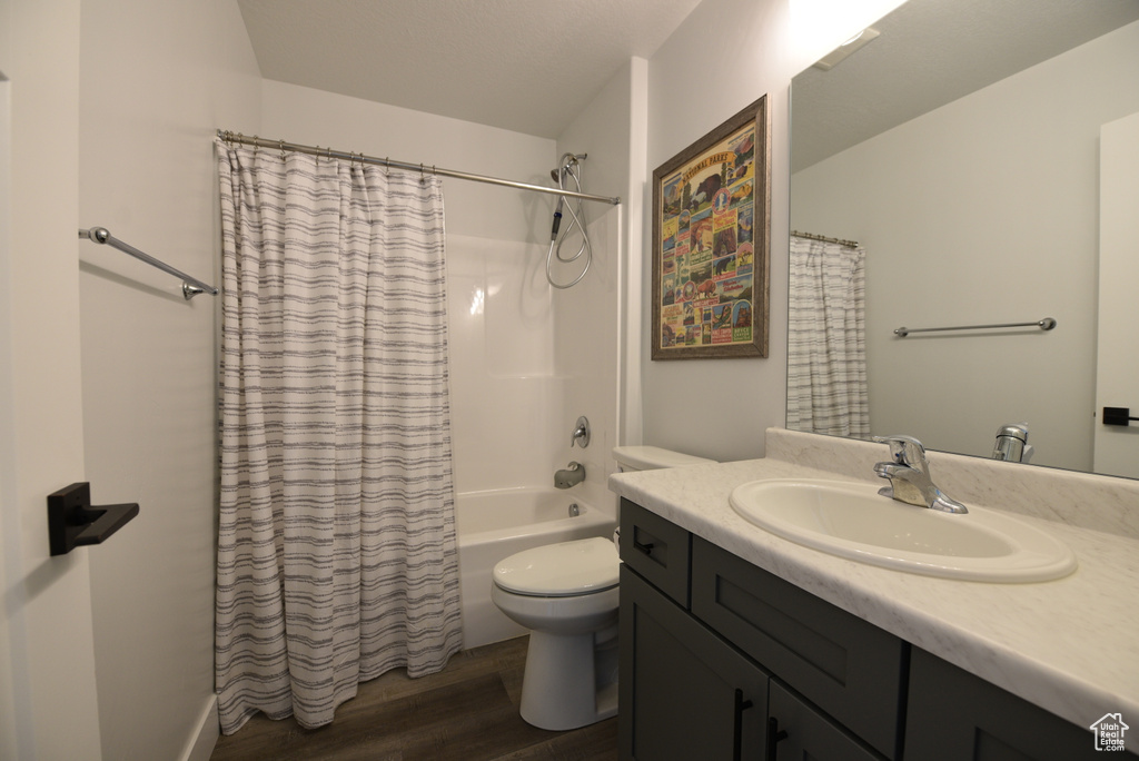 Bathroom featuring wood finished floors, vanity, and shower / bath combo with shower curtain
