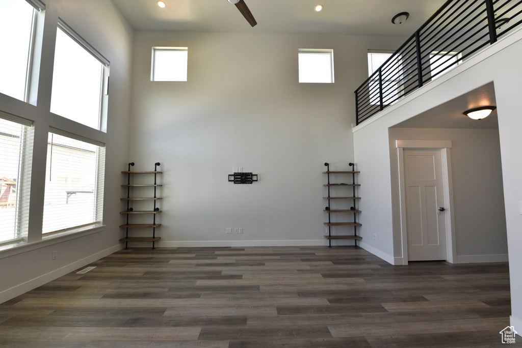 Unfurnished living room with a towering ceiling, recessed lighting, and dark wood-style floors