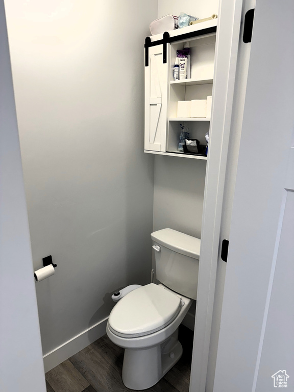 Bathroom with wood finished floors, toilet, and baseboards