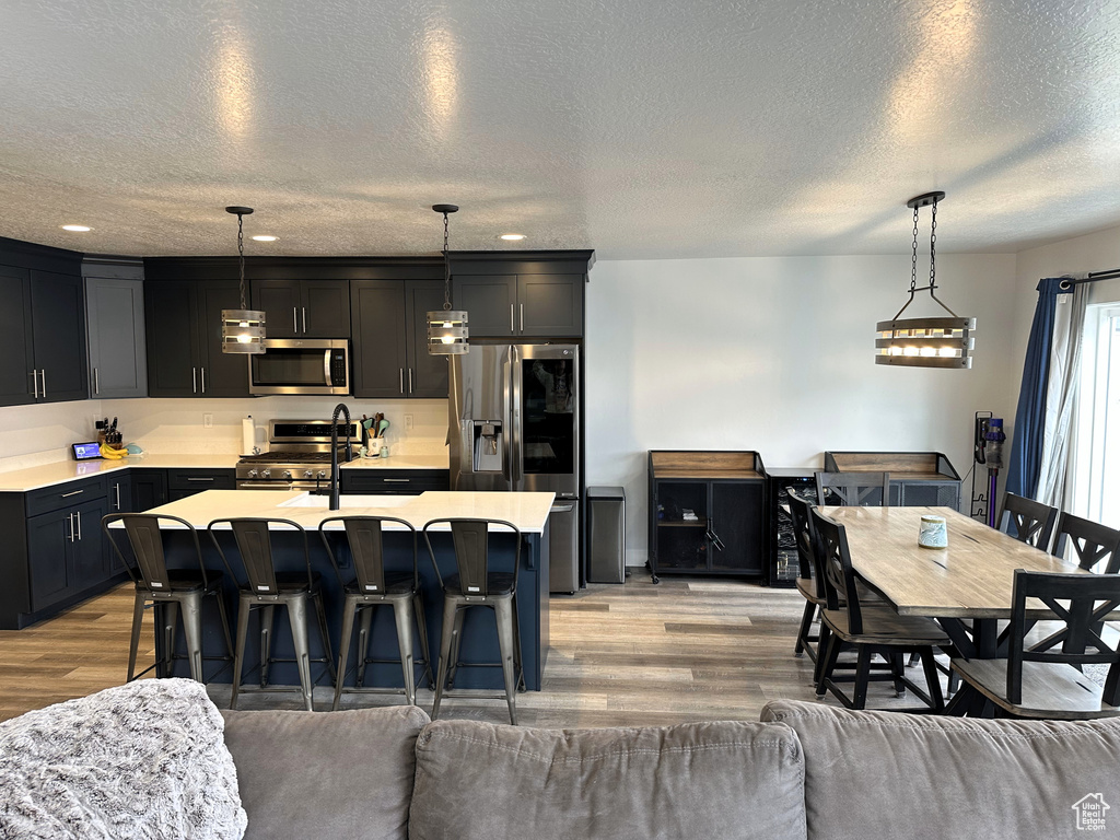 Kitchen featuring appliances with stainless steel finishes, light wood finished floors, light countertops, open floor plan, and a textured ceiling