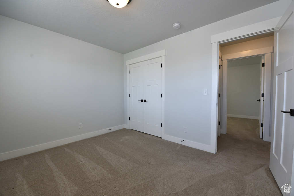 Unfurnished bedroom with carpet and a closet