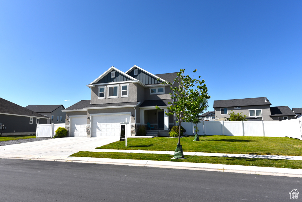 View of front of home featuring board and batten siding, driveway, a garage, and a residential view