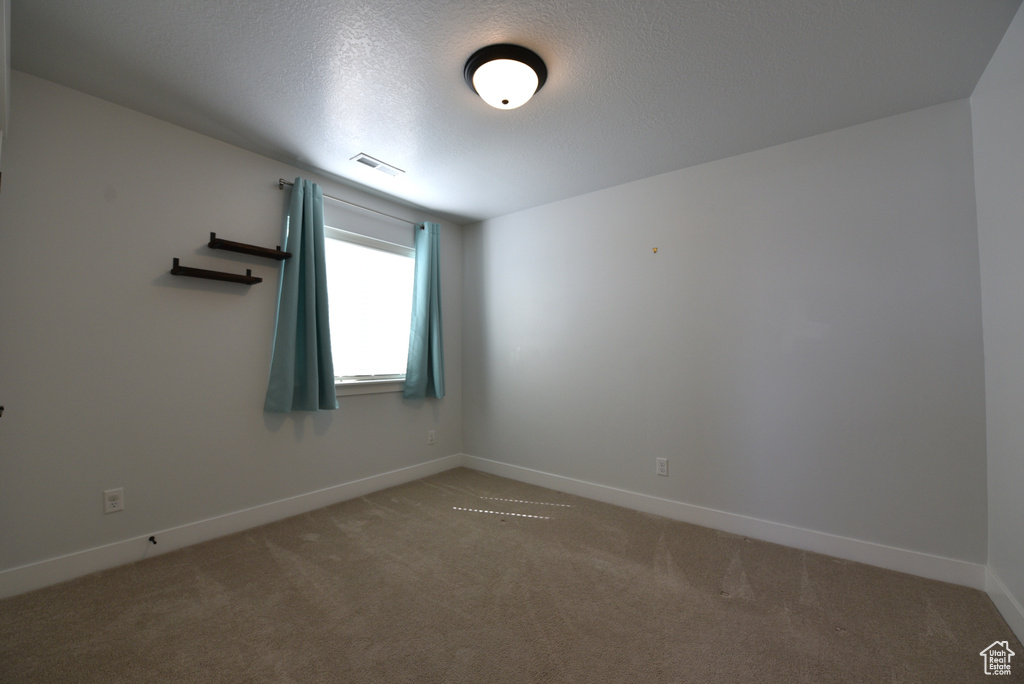 Carpeted empty room featuring baseboards and a textured ceiling