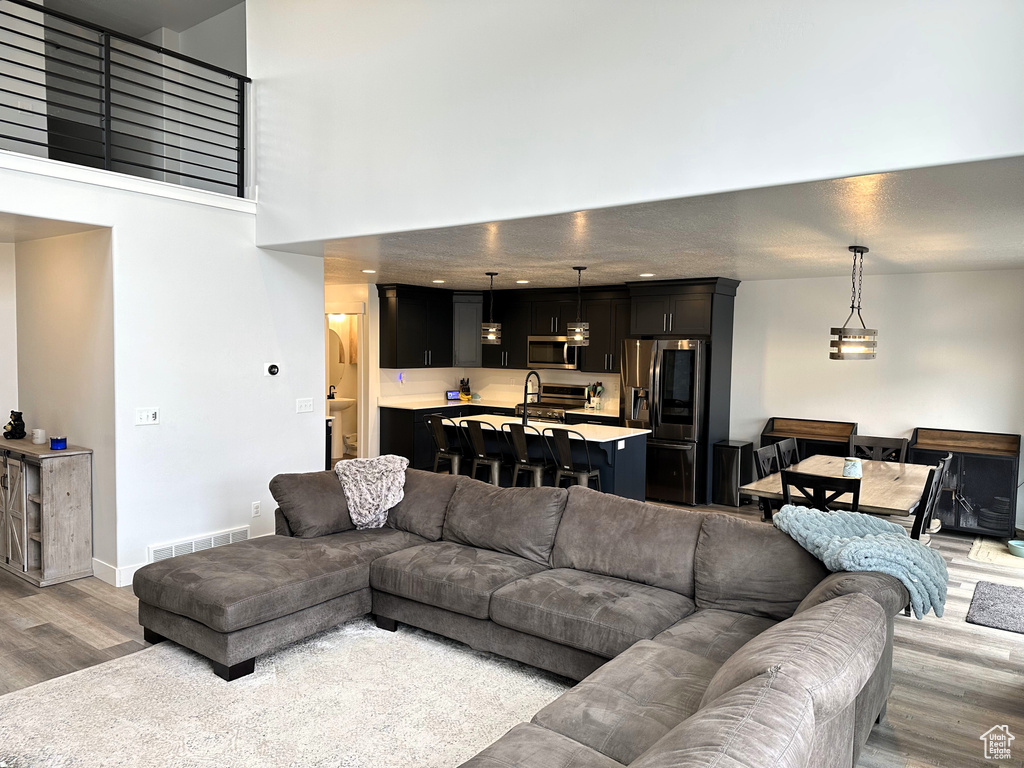 Living room featuring light wood-type flooring, baseboards, and a towering ceiling