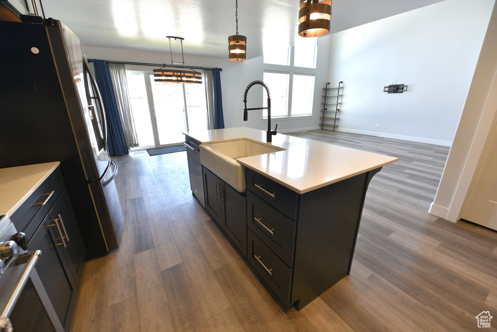 Kitchen featuring appliances with stainless steel finishes, light countertops, dark wood-style flooring, and hanging light fixtures