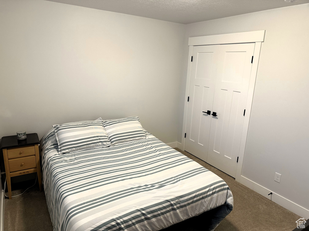 Bedroom featuring dark carpet, a closet, and baseboards
