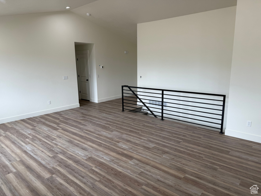 Spare room with vaulted ceiling, wood finished floors, and baseboards