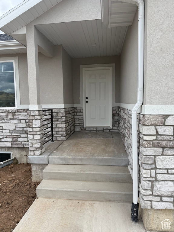 Entrance to property with stone siding and stucco siding