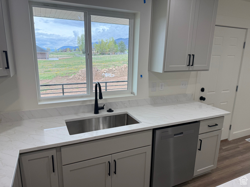 Kitchen with dishwasher, a sink, dark wood-style floors, and plenty of natural light