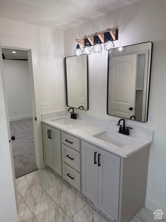 Bathroom featuring marble finish flooring, double vanity, and baseboards